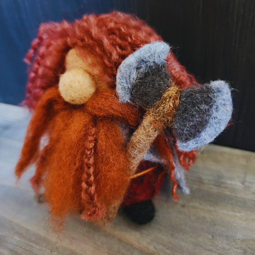 Close-up of a needle-felted Gimli the Dwarf, featuring braided red hair and beard, holding a felted axe.