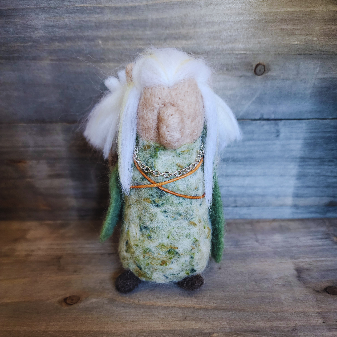 Full-body shot of a needle-felted Legolas figure with long white-blonde hair, dressed in green and patterned fabric.