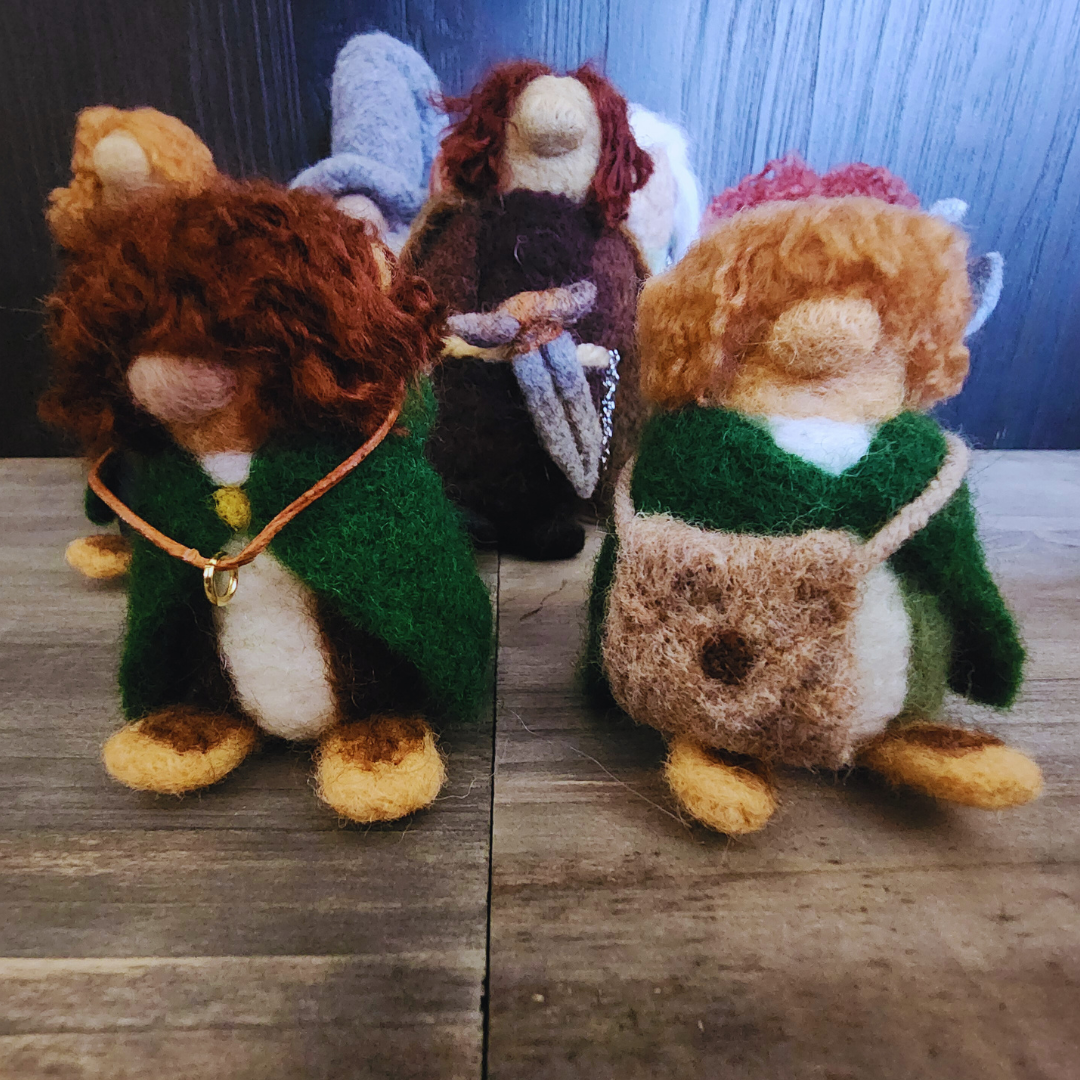 Group shot of the four hobbits (Frodo, Sam, Merry, Pippin) and Aragorn in the background. Focus is on Frodo and Sam in the foreground.