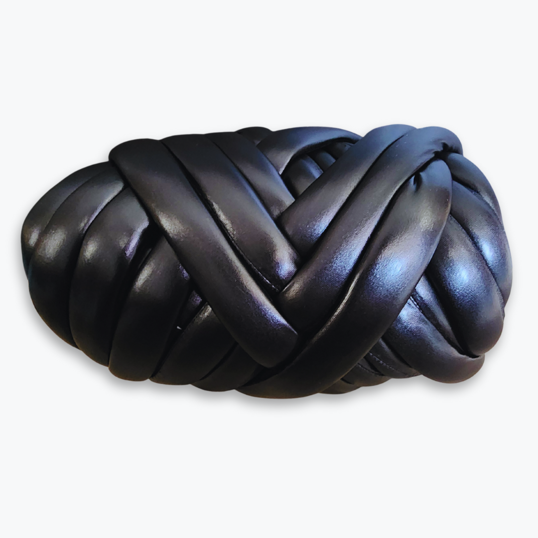 A large skein of handmade chunky yarn in matte black, showing its thick, braided texture.
