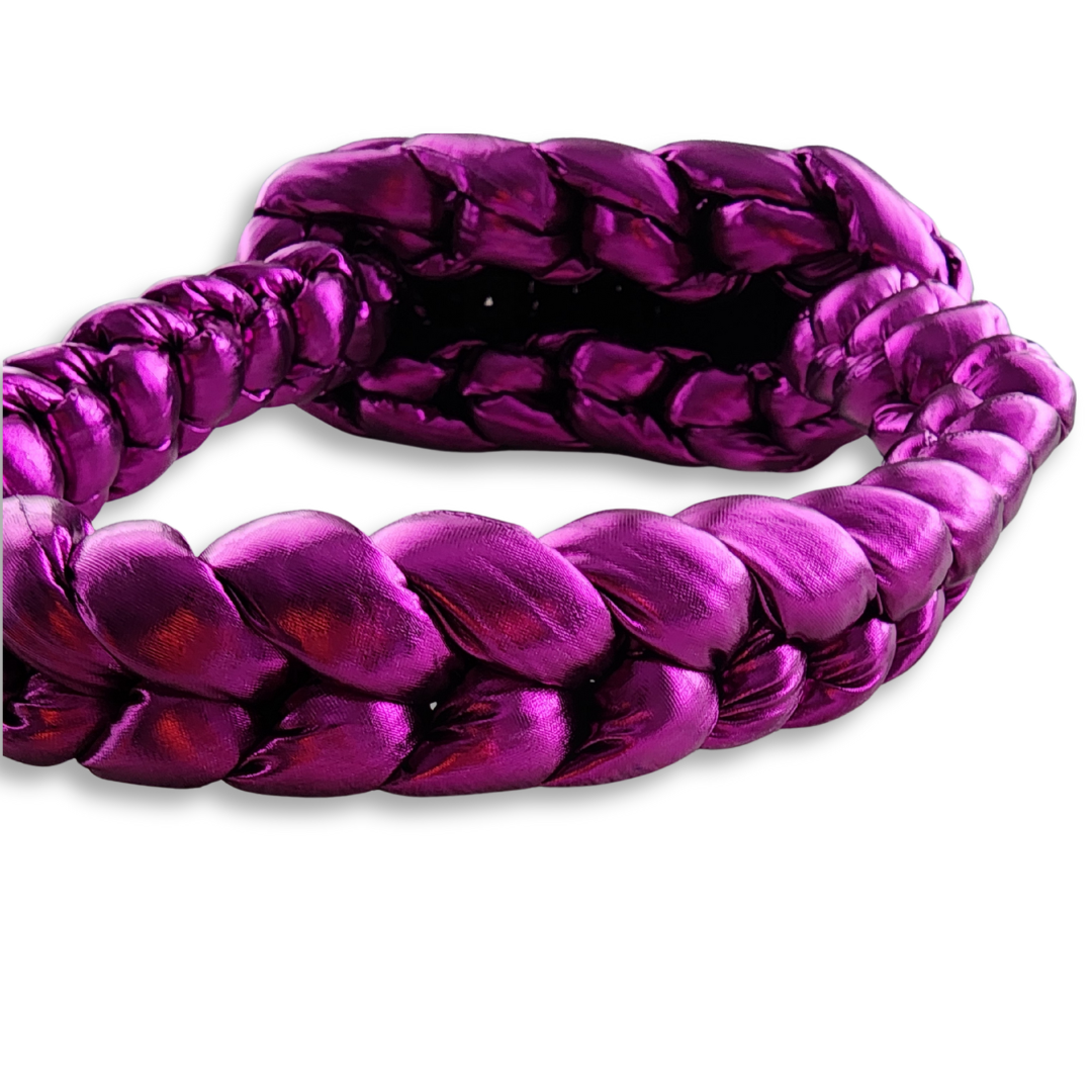 A close-up view of the braided handle of a handmade chunky knit handbag in shimmering metallic fuchsia, showing its texture.