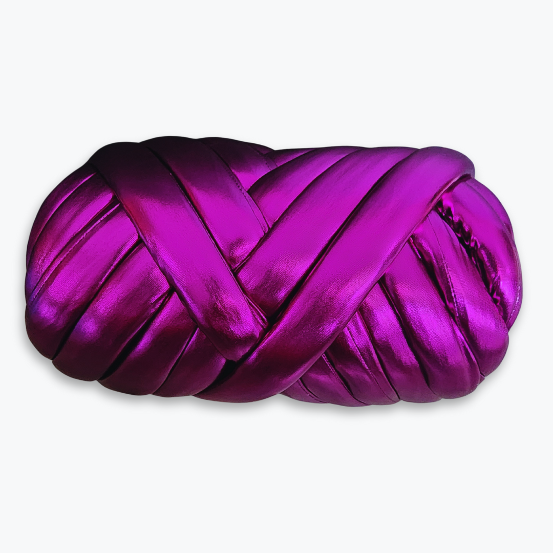 A large skein of handmade chunky yarn in shimmering metallic fuchsia, showing its thick, braided texture.