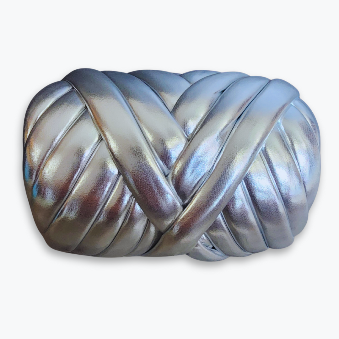 A large skein of handmade chunky yarn in shimmering metallic silver, showing its thick, braided texture.
