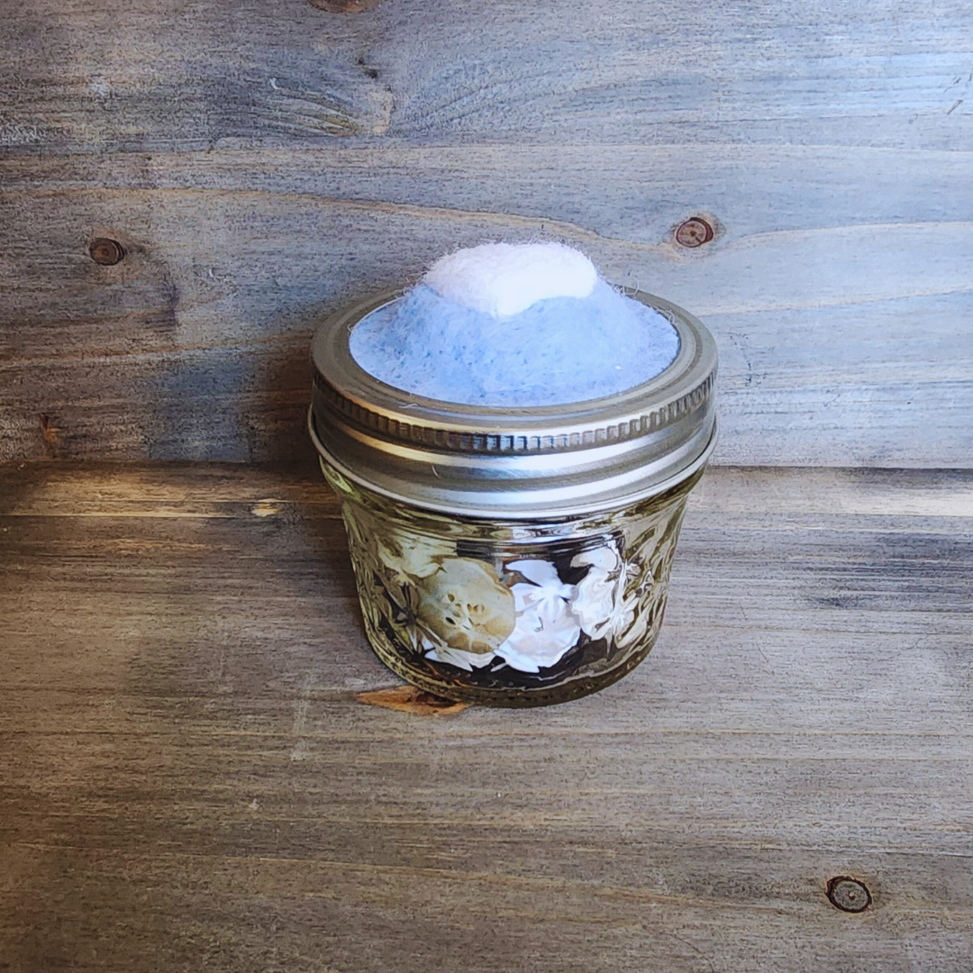 A side profile view of the blue heart jar showing the "quilted" texture of the glass and the buttons stored inside.