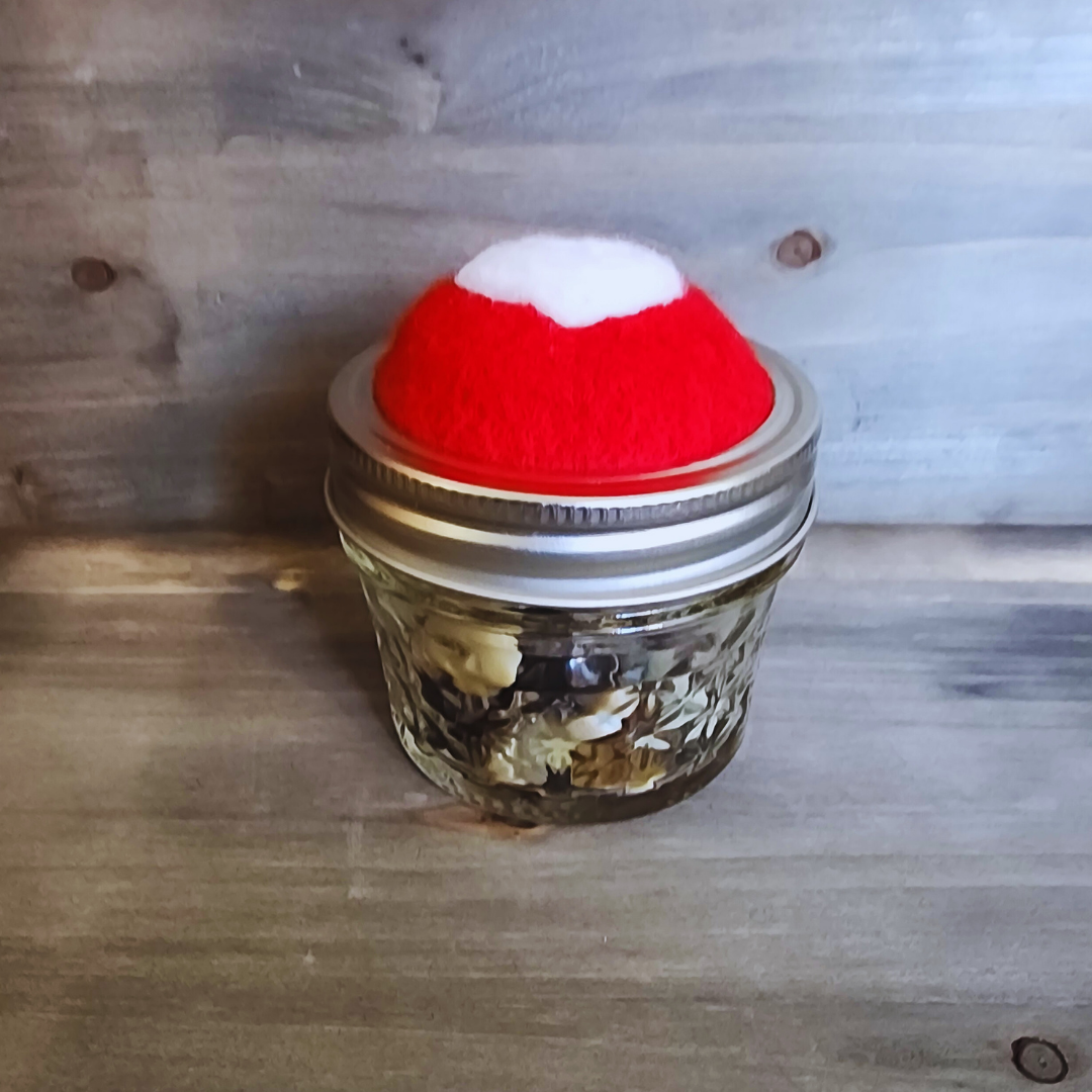 A side profile of the red heart jar emphasizing the bright wool topper and the button stash inside.