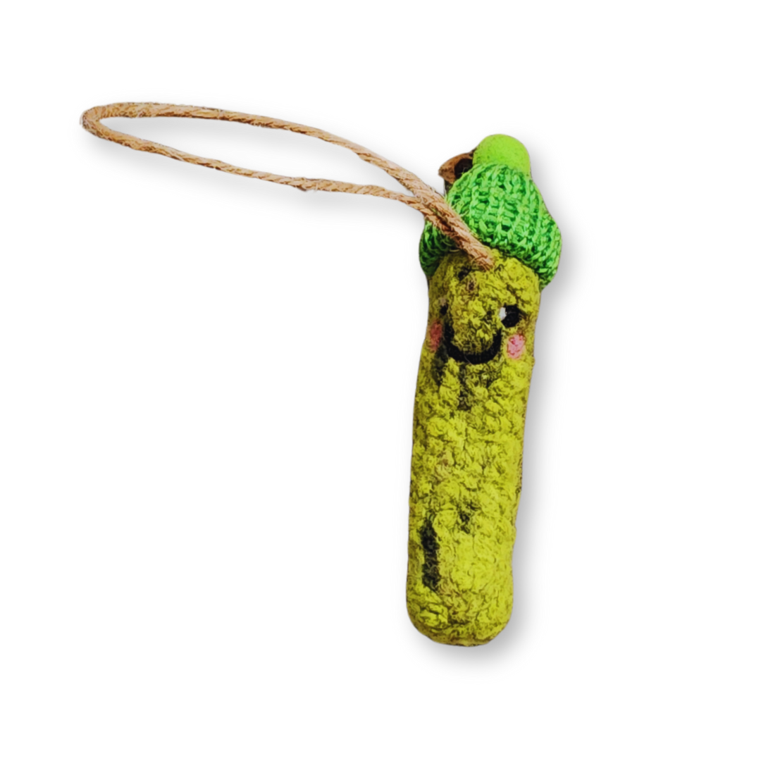 A bright green, textured felted pickle ornament with a smiling expression, wearing a hand-crocheted green winter hat, hanging from a jute string.