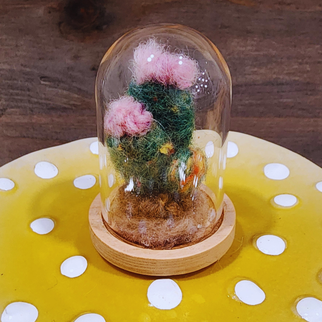 A handmade felted Flowering Cactus terrarium with two pink blooms and green body in a glass dome.