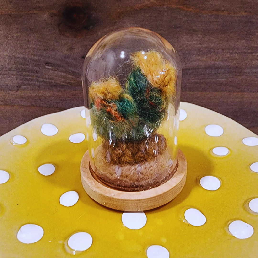 A handmade needle-felted Flowering Cactus terrarium with bright yellow felt blooms, housed in a glass dome.
