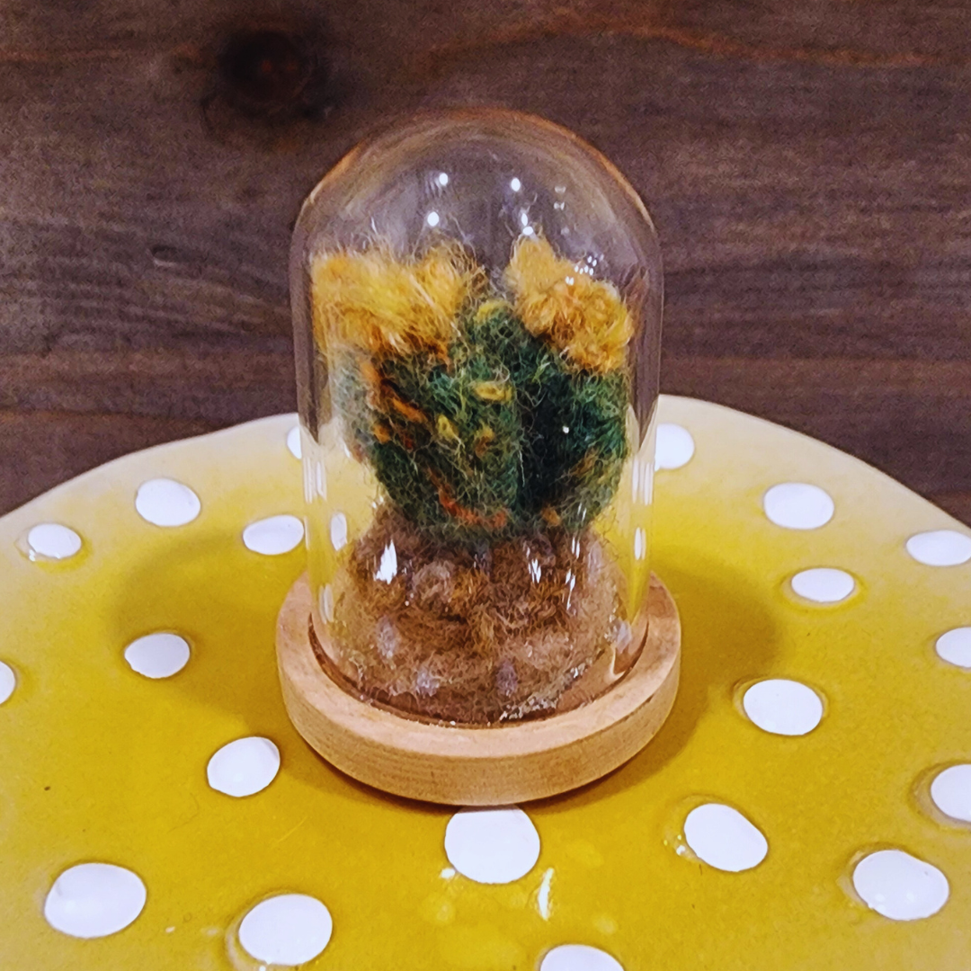 A handmade felted Flowering Cactus terrarium with vibrant yellow blooms in a glass dome.
