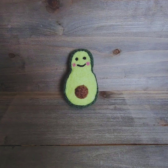 A short video demonstrating the durability of the avocado toy as a pair of hands squeezes and turns it to show the 360-degree felted construction and firm, wool-filled core.